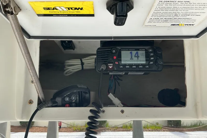 Slide: The Image of 2017 Seahunt 225 Triton boat radio compartment with Sea Tow sticker and communication equipment. - 11