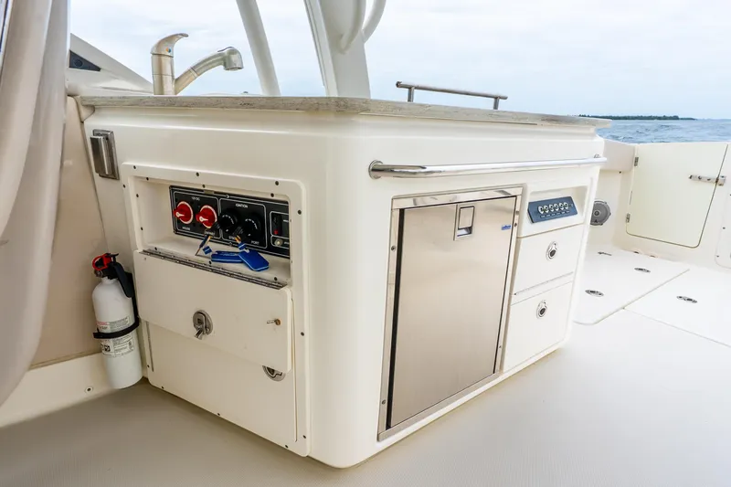 Slide: The Image of 2017 Boston Whaler 320 Vantage boat interior with control panel and storage compartments. - 25