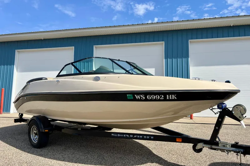 The Image of 2007 Bombardier Seadoo Utopia boat on trailer, parked outside blue building. - 1