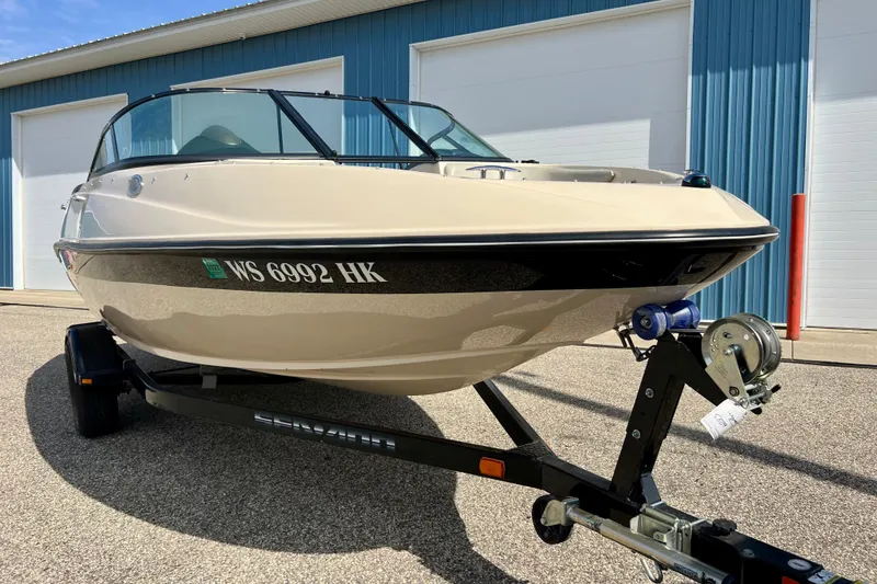 Slide: The Image of 2007 Bombardier Seadoo Utopia boat on trailer, parked outside blue building. - 2