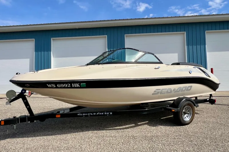 Slide: The Image of 2007 Bombardier Seadoo Utopia boat on trailer, parked outside blue building. - 6