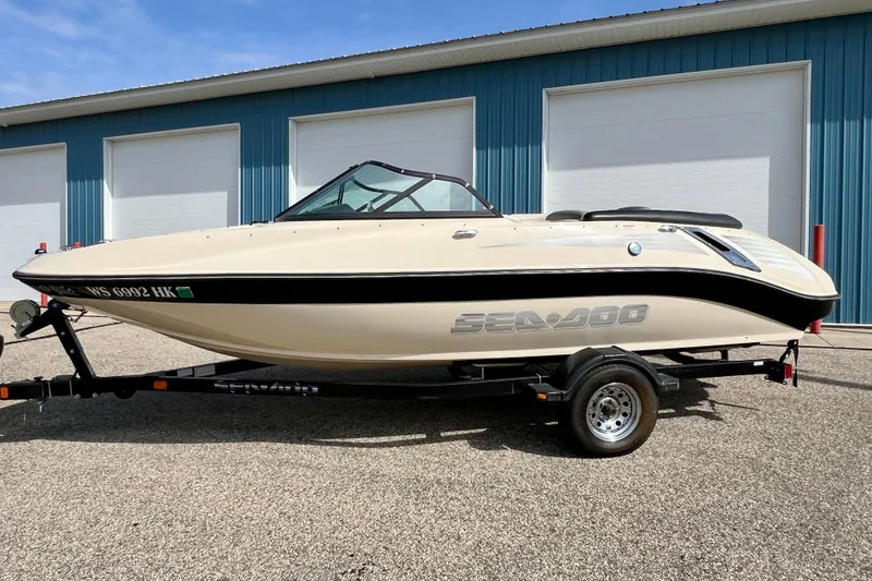Slide: The Image of 2007 Bombardier Seadoo Utopia boat on trailer, parked outside blue building. - 7
