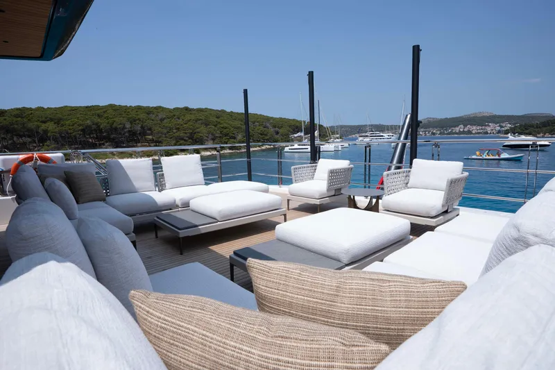 Slide: The Image of Luxurious 2025 Alpha 100 Squalo yacht deck with plush seating, overlooking serene waters and distant boats. - 15