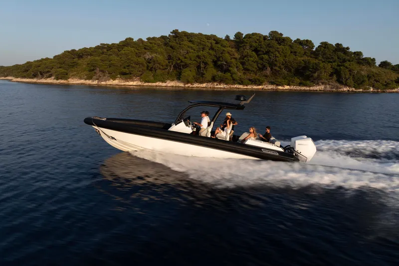 Slide: The Image of 2025 Alpha 100 Squalo Co Ownership boat cruising near a lush island. - 42