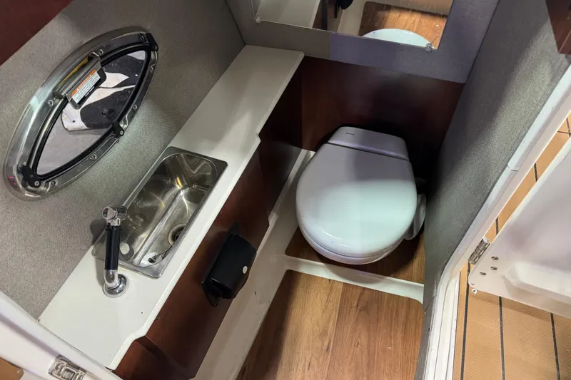 Slide: The Image of 2021 Chaparral 287 SSX boat bathroom with sink, toilet, and porthole window. - 11