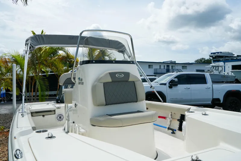 Slide: The Image of 2025 Key West 210 Bay Reef boat with seating and canopy, parked near a white truck. - 11