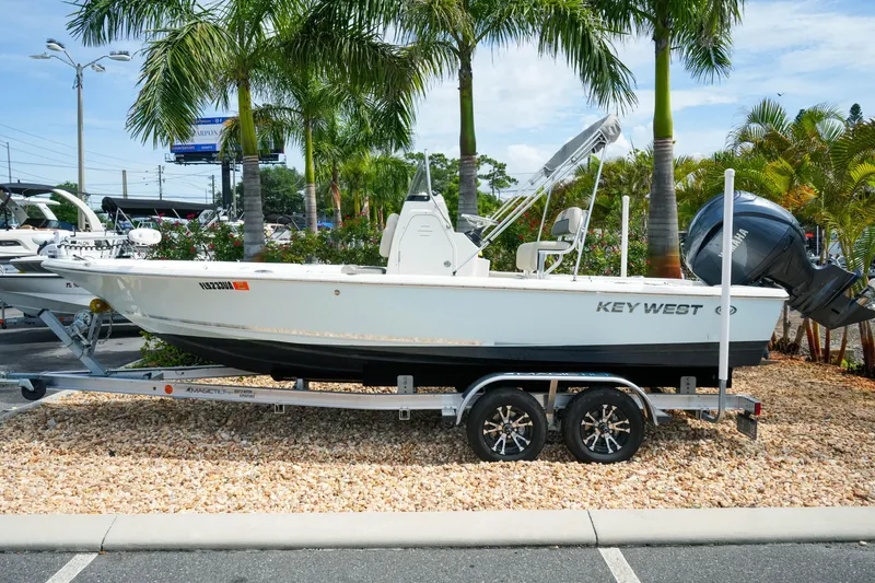 Slide: The Image of 2025 Key West 210 Bay Reef boat on trailer, surrounded by palm trees. - 2