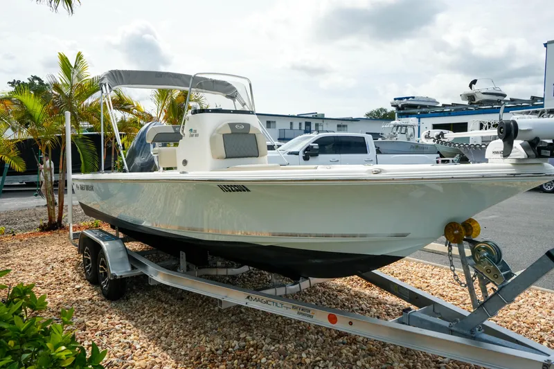 Slide: The Image of 2025 Key West 210 Bay Reef boat on trailer, parked outdoors near palm trees. - 9