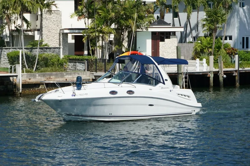 The Image of 2008 Sea Ray Sundancer 260 cruising on a sunny waterfront near modern homes. - 1