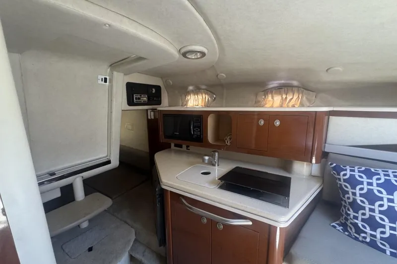 Slide: The Image of Interior of 2008 Sea Ray Sundancer 260, featuring kitchenette and cozy cabin space. - 31