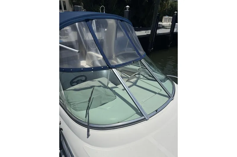 Slide: The Image of 2008 Sea Ray Sundancer 260 boat with blue canopy and windshield, docked by the water. - 49
