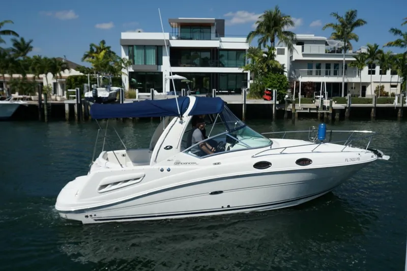 Slide: The Image of 2008 Sea Ray Sundancer 260 cruising on a sunny waterfront with modern homes in the background. - 4
