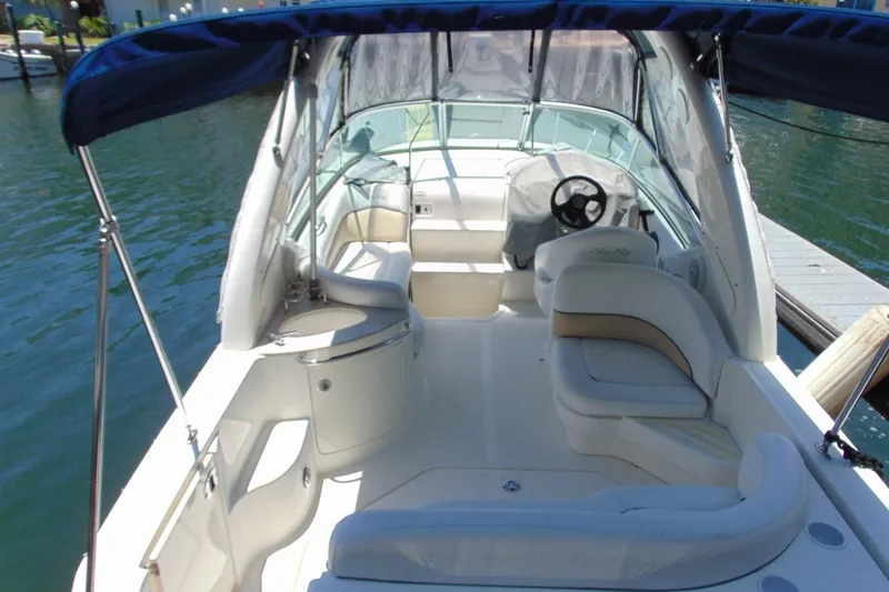 Slide: The Image of 2008 Sea Ray Sundancer 260 boat interior with seating and steering wheel, docked on calm water. - 6