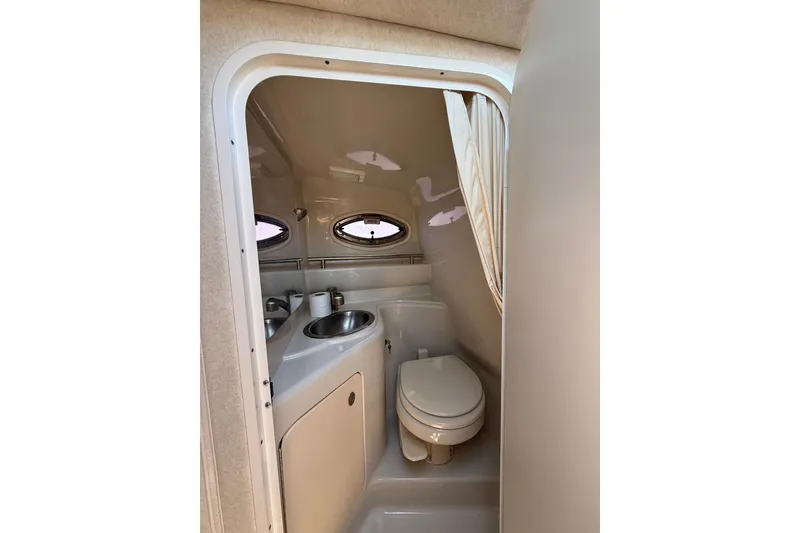 Slide: The Image of Compact bathroom in 2009 Sea Ray 240 Sundancer boat, featuring toilet and sink. - 16