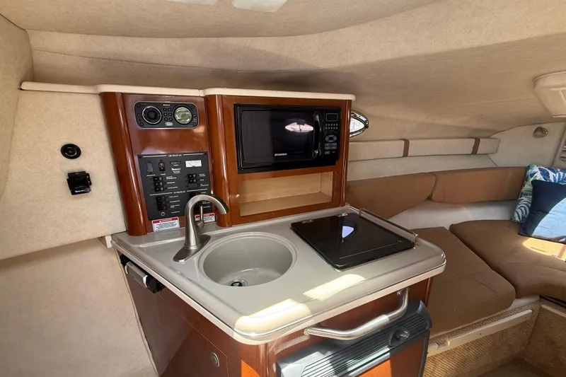 Slide: The Image of 2009 Sea Ray 240 Sundancer cabin interior with kitchenette, sink, and seating area. - 17