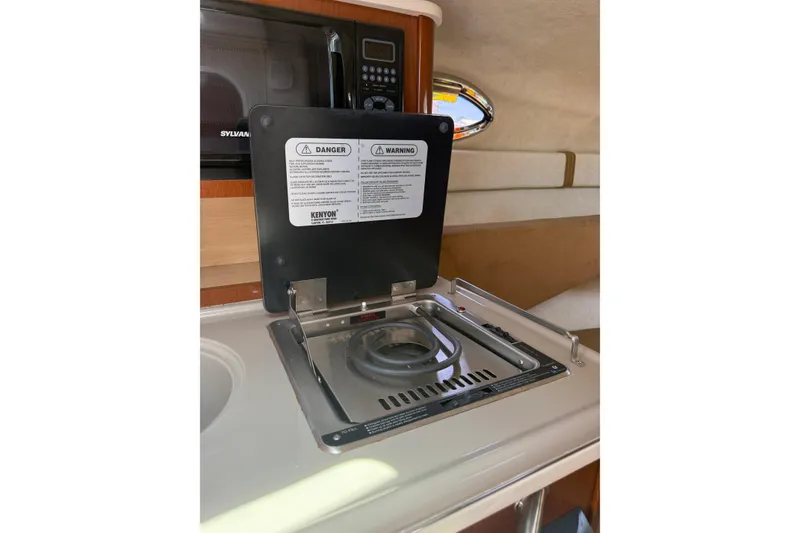 Slide: The Image of 2009 Sea Ray 240 Sundancer interior with stove and microwave in cabin kitchen. - 18