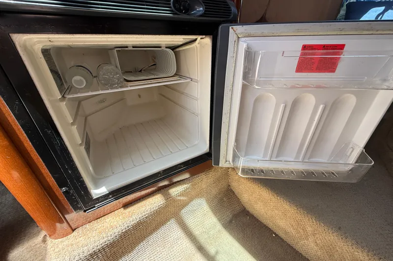 Slide: The Image of Open mini fridge inside 2009 Sea Ray 240 Sundancer boat, showing interior shelves and door compartments. - 19