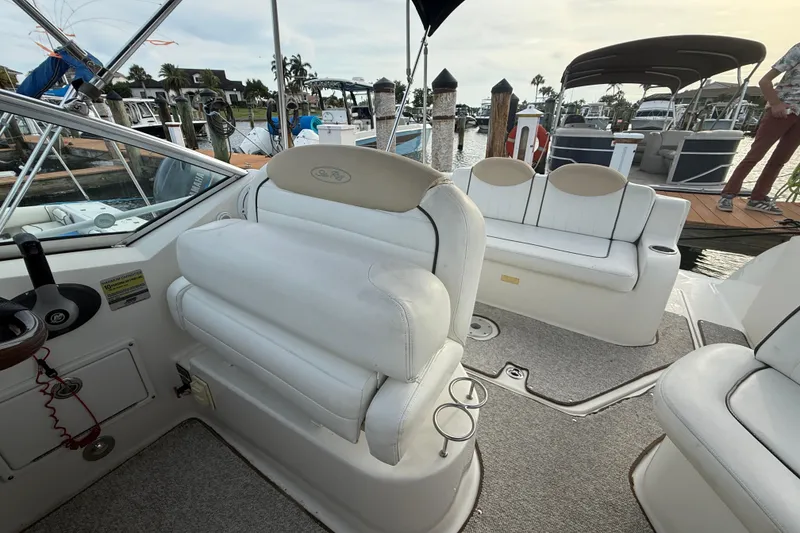 Slide: The Image of 2009 Sea Ray 240 Sundancer boat interior with white seating and dock view. - 7