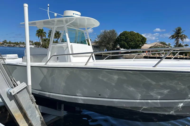 Slide: The Image of 2002 Regulator 32 Forward Seating boat docked by waterfront homes under clear blue sky. - 33