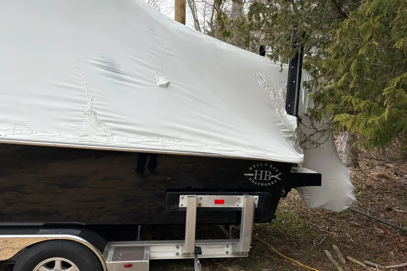 Slide: The Image of 2020 Hells Bay Ester boat covered, on trailer, surrounded by trees. - 4