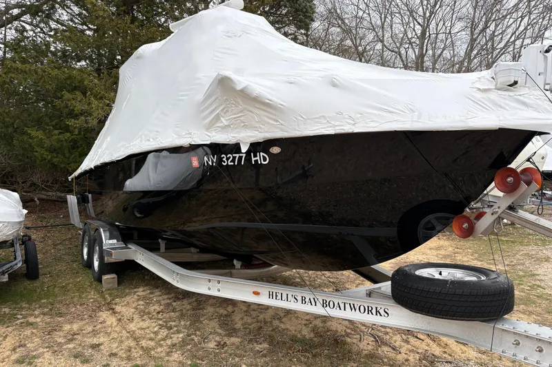 The Image of 2020 Hells Bay Ester boat covered on trailer, parked outdoors. - 1