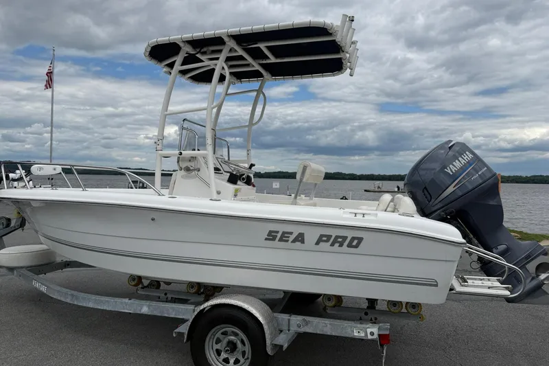 Slide: The Image of 2005 Sea Pro 190 Center Console boat on trailer by a lake under cloudy sky. - 2