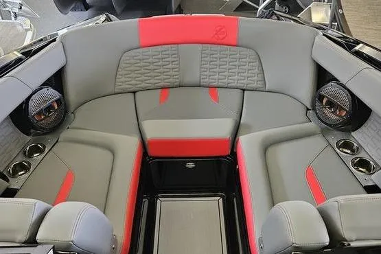 Slide: The Image of 2025 MasterCraft X22 boat interior with gray and red seating, featuring built-in speakers. - 2