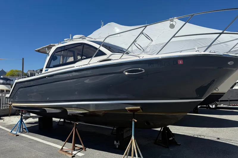 Slide: The Image of 2022 Cutwater C-24 Coupe boat on stands, displayed outdoors under clear blue sky. - 13