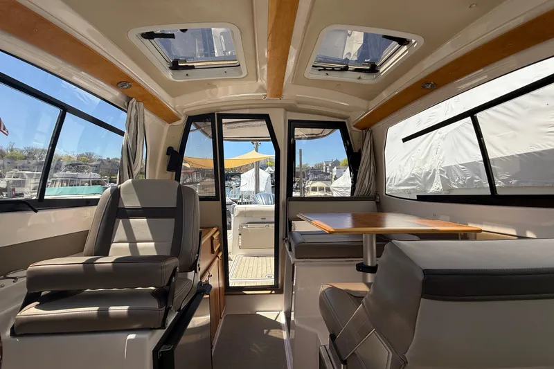 Slide: The Image of Interior of 2022 Cutwater C-24 Coupe, featuring seating and a table with marina view. - 22