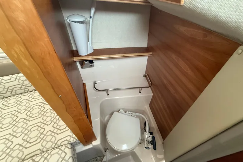 Slide: The Image of 2022 Cutwater C-24 Coupe interior bathroom with compact toilet and wooden accents. - 46