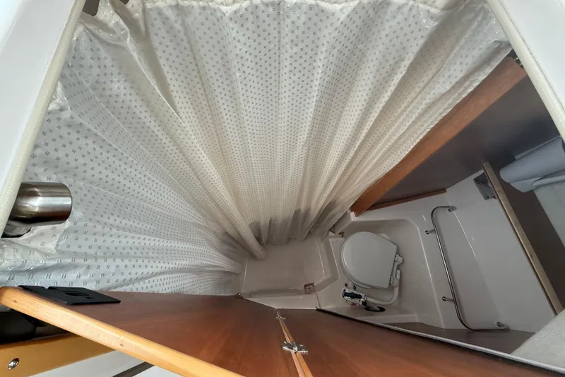 Slide: The Image of Bathroom interior of 2022 Cutwater C-24 Coupe with shower curtain and toilet. - 48