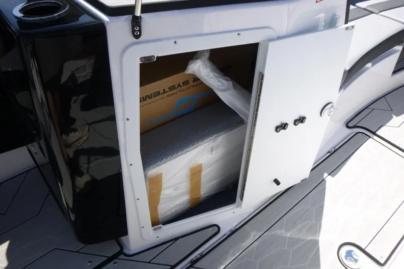 Slide: The Image of Open storage compartment on 2026 Yamaha Boats 222XD, revealing packaged items inside. - 10
