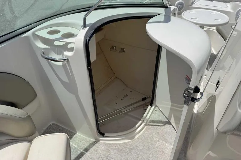 Slide: The Image of 2005 Sea Ray 220 Sundeck boat interior with open storage compartment and cup holders. - 18