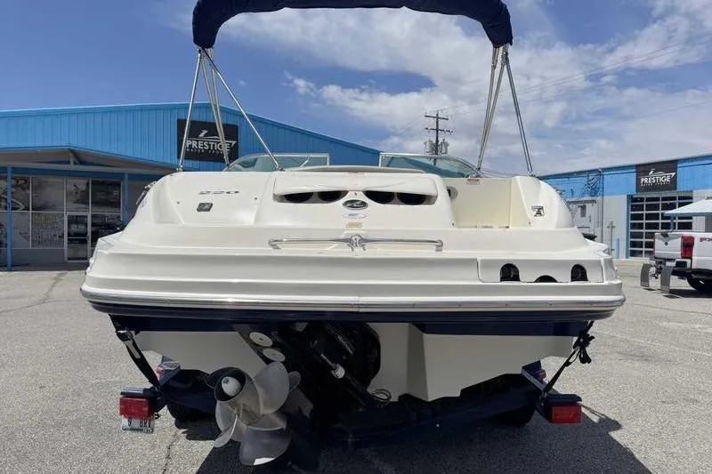 Slide: The Image of 2005 Sea Ray 220 Sundeck boat with blue canopy, parked outside a dealership. - 8