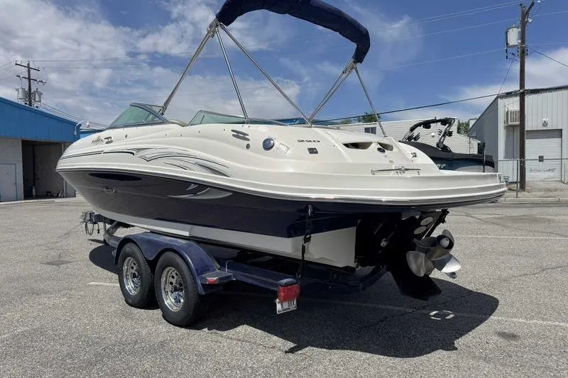 Slide: The Image of 2005 Sea Ray 220 Sundeck boat on trailer, parked outdoors under blue sky. - 9