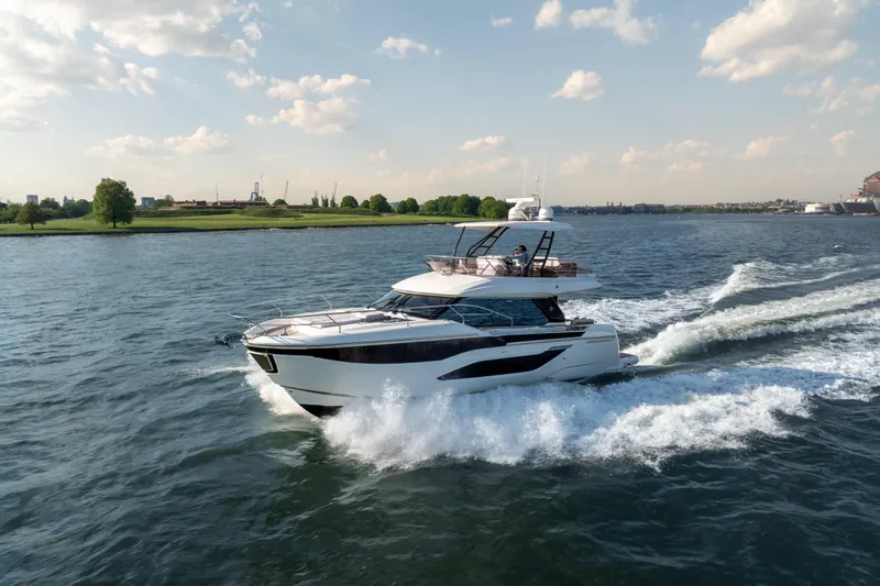 Slide: The Image of 2025 Prestige F4.9 yacht cruising on a scenic waterway under a partly cloudy sky. - 11