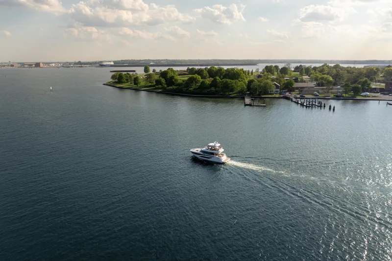 Slide: The Image of A Prestige F4.9 yacht cruising near a lush, green island under a partly cloudy sky. - 4