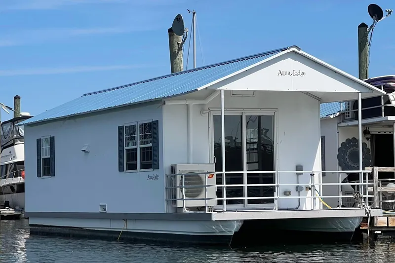 The Image of 2017 Catamaran Cruisers Aqualodge houseboat docked in marina, featuring blue roof and white exterior. - 1