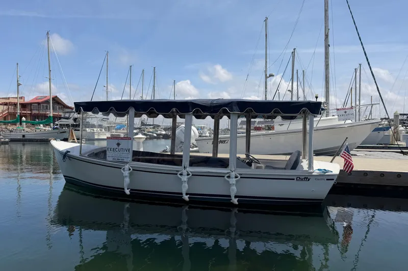The Image of 1996 Duffy Classic 21 electric boat docked in a marina with sailboats. - 1