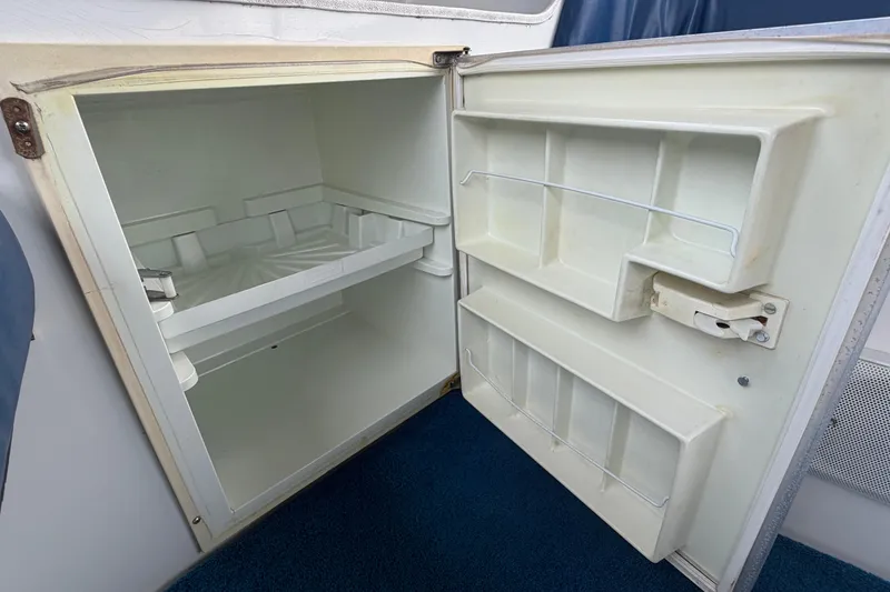 Slide: The Image of Open refrigerator inside a 1996 Duffy Classic 21 boat, showing empty shelves and door compartments. - 24