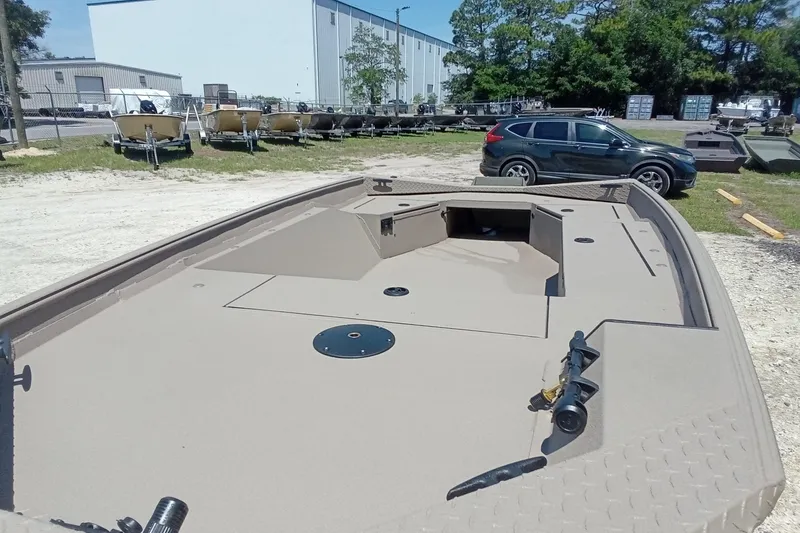 Slide: The Image of 2026 Alweld 1652 Invader boat in outdoor showroom, beige deck, parked cars nearby. - 5