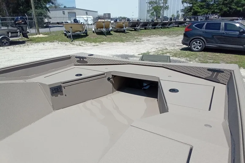 Slide: The Image of 2026 Alweld 1652 Invader boat interior with storage compartments, parked outdoors. - 6