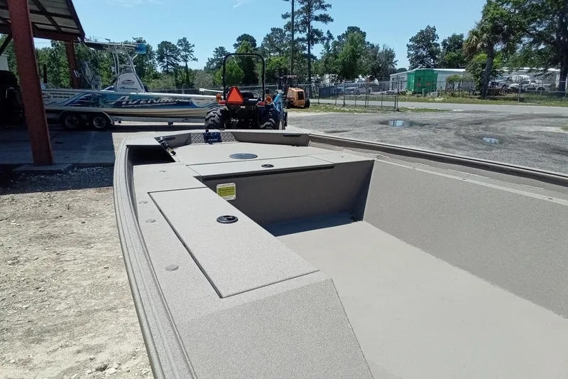 Slide: The Image of 2026 Alweld 1652 Invader boat interior, parked outdoors with trees and equipment nearby. - 7