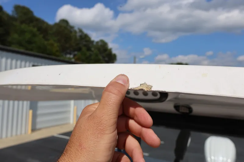 Slide: The Image of Close-up of a hand inspecting damage on a 2022 Sea Hunt Ultra 239 SE boat. - 22