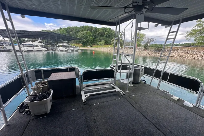 Slide: The Image of Houseboat deck view on serene lake, Sumerset 14x64, 1992 model, with docked boats nearby. - 13