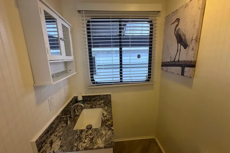 Slide: The Image of Small bathroom in a 1992 Sumerset 14x64 houseboat with granite countertop and heron artwork. - 8