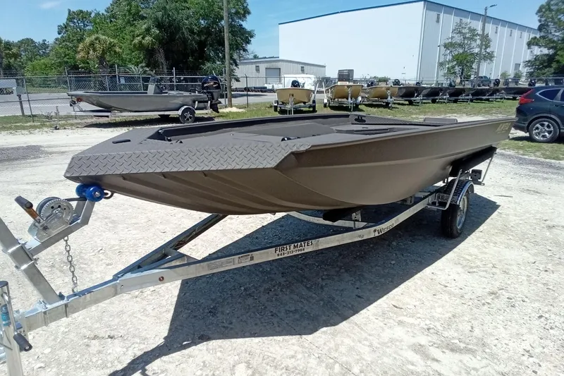 Slide: The Image of 2026 Alweld 1652 Invader boat on trailer, parked outdoors near industrial buildings. - 16