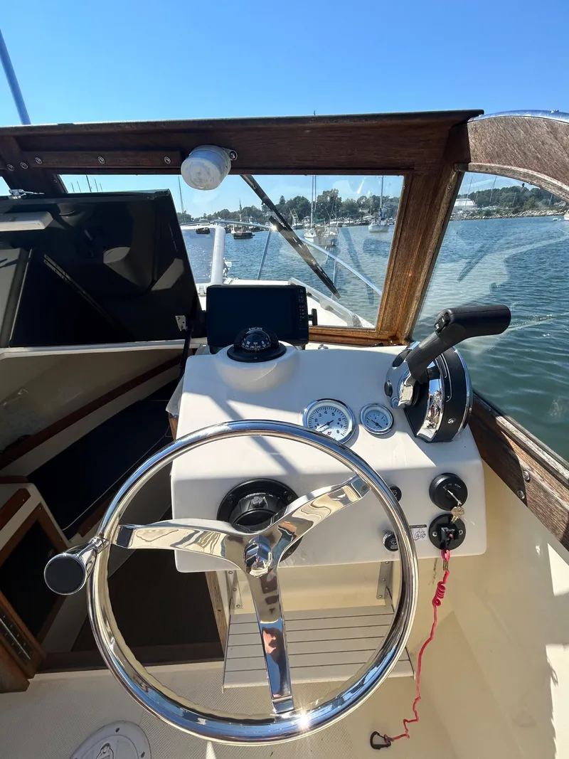 Slide: The Image of 2021 Seaway 21 Seafarer Cuddy boat helm with steering wheel and controls, on a sunny day. - 11