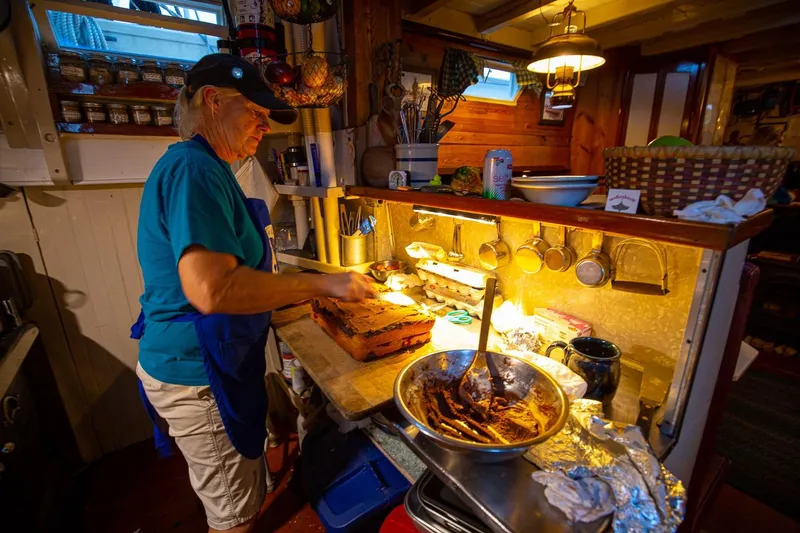Slide: The Image of Woman cooking in a cozy kitchen aboard a 1962 Classic Coasting Schooner. - 10