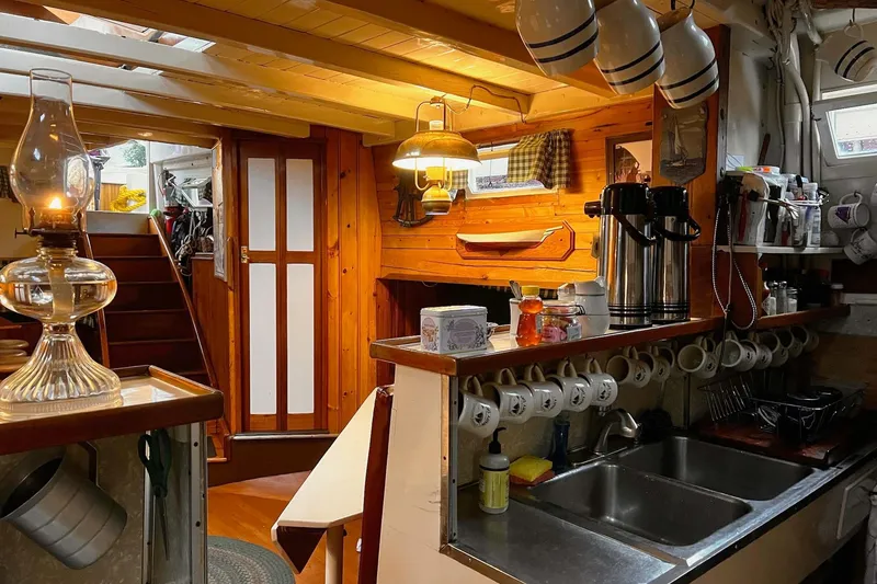 Slide: The Image of Cozy 1962 Classic Coasting Schooner interior with wooden decor and vintage lighting. - 11